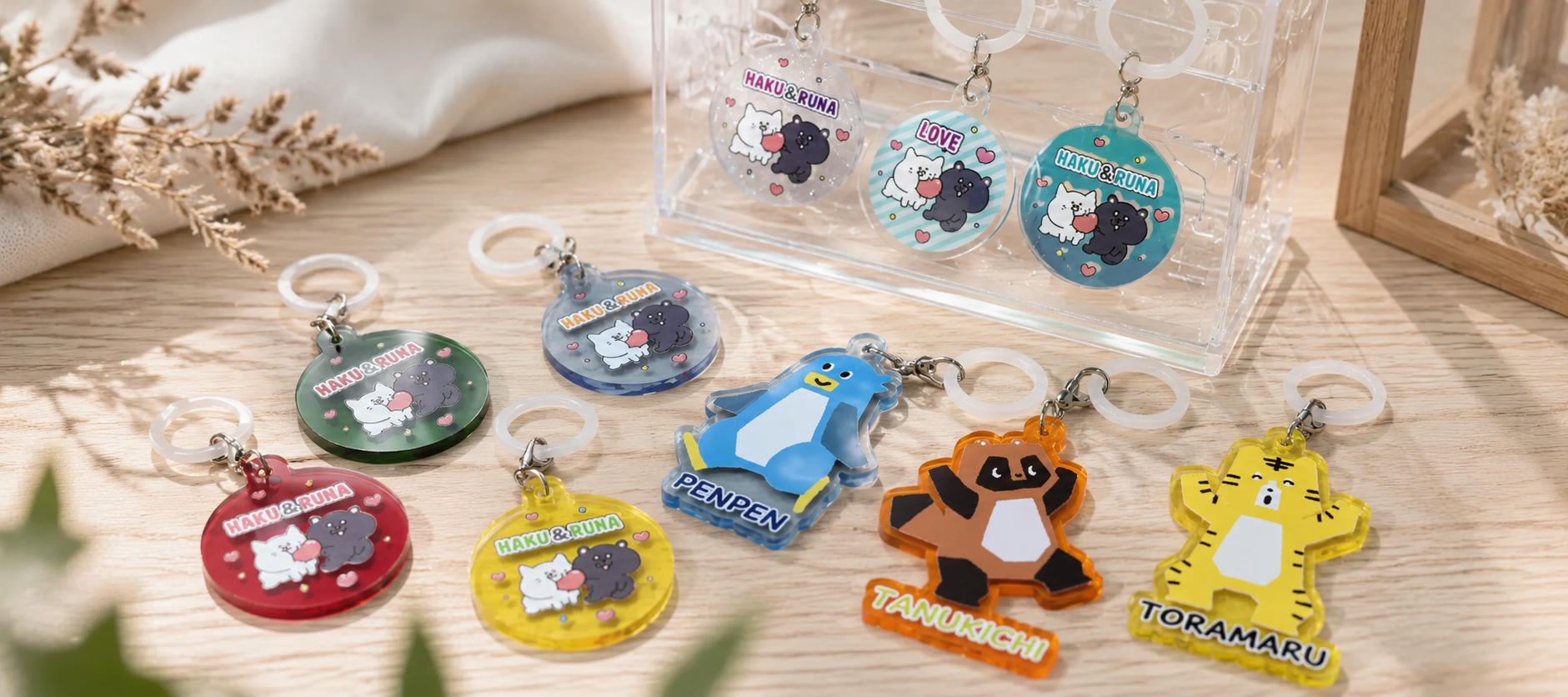 Assorted cute cat-themed keychains with round disks and animal charms on a wooden surface.