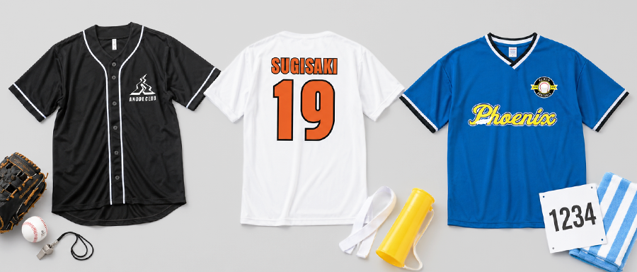 Three jerseys displayed: black with white trim on the left, white Sugisaki 19 in the center, blue Phoenix jersey on the right; gear includes a baseball glove, ball, lanyard, yellow water bottle, towel, and bib 1234 nearby.